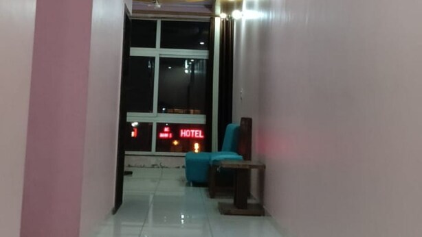 A hotel corridor with a shiny tiled floor, pink walls, and a blue seating area. - Hotel Blue Diamond (Shri Madhopur)