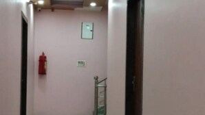 A hallway with a tiled floor, pink walls, and recessed ceiling lights. - Hotel Blue Diamond (Shri Madhopur)