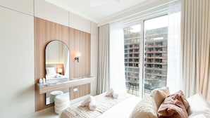 Ein modernes Hotelzimmer mit einem großen Bett, einem Einbauschrank, einem Schminktisch mit Spiegel und Blick auf ein Gebäude durch das Fenster.