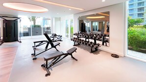 Ein modernes Fitnessstudio mit Trainingsgeräten, großen Fenstern und Blick auf die Stadt.