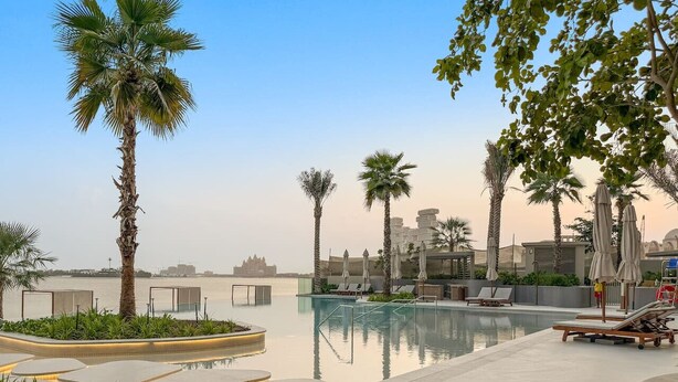 A pool area with lounge chairs and palm trees. - FIRST CLASS | 4BR | Elegant Beach House Retreat (Palm)