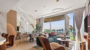 A modern living room with a dining area, large windows, and a view of palm trees. - FIRST CLASS | 4BR | Elegant Beach House Retreat (Palm)