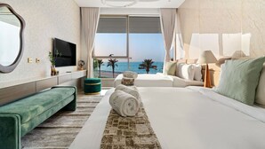 A modern hotel room with a large bed, a green sofa, a TV, and a view of the sea. - FIRST CLASS | 4BR | Elegant Beach House Retreat (Palm)