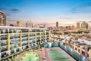 A multi-story hotel with a rooftop tennis court and a swimming pool.