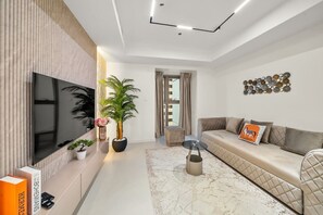 A modern living room with a flat-screen TV, a sofa, a coffee table, and decorative items. - FIRST CLASS | 2BR | Luxury Marina Bliss (Marina)