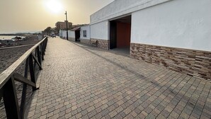 Ein gepflasterter Weg mit Holzgeländer, der zu einem Gebäude mit offener Tür führt.