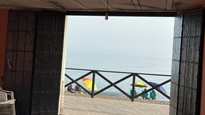 Blick auf den Strand von einer überdachten Terrasse mit Holzboden und Geländer, mit Meerblick.