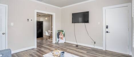 A living room with a ceiling fan, a flat-screen TV mounted on the wall, a marble coffee table, and a grey sofa.