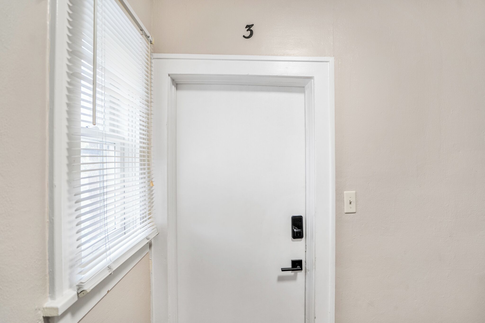 Une porte blanche avec le chiffre « 3 » au-dessus, une serrure et une poignée.