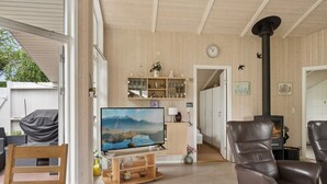 Un salon chaleureux avec un téléviseur, des fauteuils en cuir, une cheminée et un décor intérieur en bois.