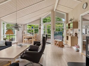 A spacious living area with a dining table, chairs, a sofa, a television, and a fireplace.