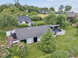 A residential property with a large deck, a covered outdoor seating area, and a view of the sea.