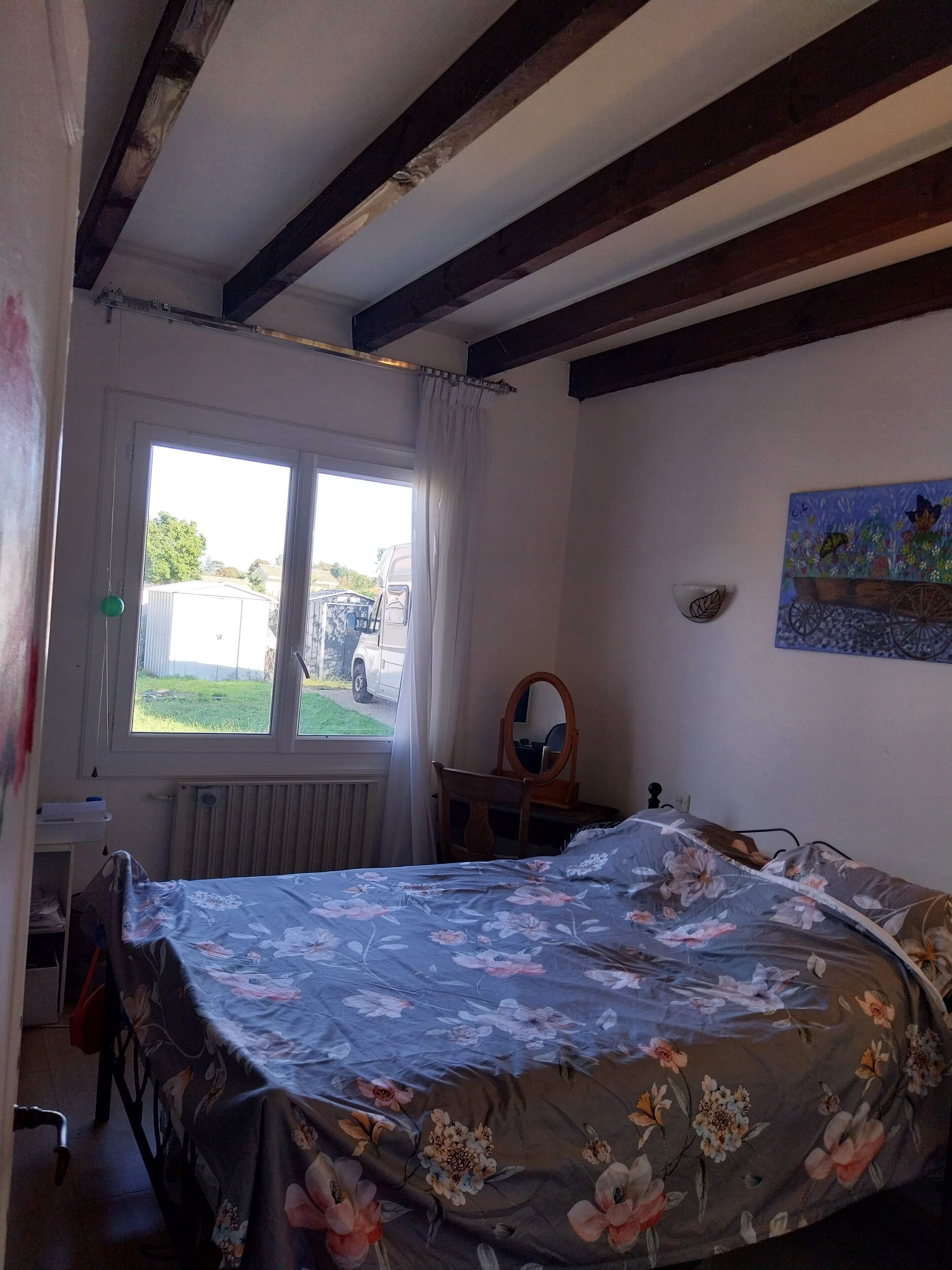 A bedroom with a bed, a window, a radiator, a desk, and a chair.