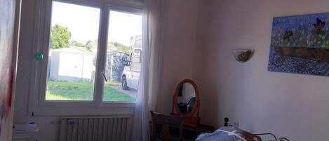 A bedroom with a bed, a window, a radiator, a desk, and a chair.
