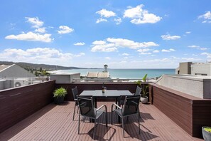 Une terrasse sur le toit, avec une table et des chaises, offrant une vue sur la côte.