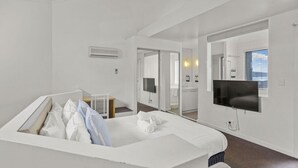 Een moderne hotelkamer met een groot bed, een televisie, een bureau en een badkamer zichtbaar door een geopende deur.