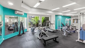 Een moderne sportschool met diverse fitnessapparaten, een grote spiegel en uitzicht op groen.