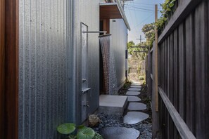 A narrow pathway with stepping stones leading to a wooden gate, surrounded by a metal fence and a wooden fence.