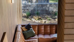 Ein modernes Interieur mit einem Ledersofa, einem kleinen runden Tisch und einer Holzbank.
