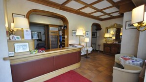 A reception area with a wooden reception desk, a red carpet, and a seating area with a table and chairs.