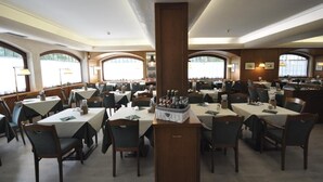 A restaurant with multiple tables and chairs, large windows, and a central column.
