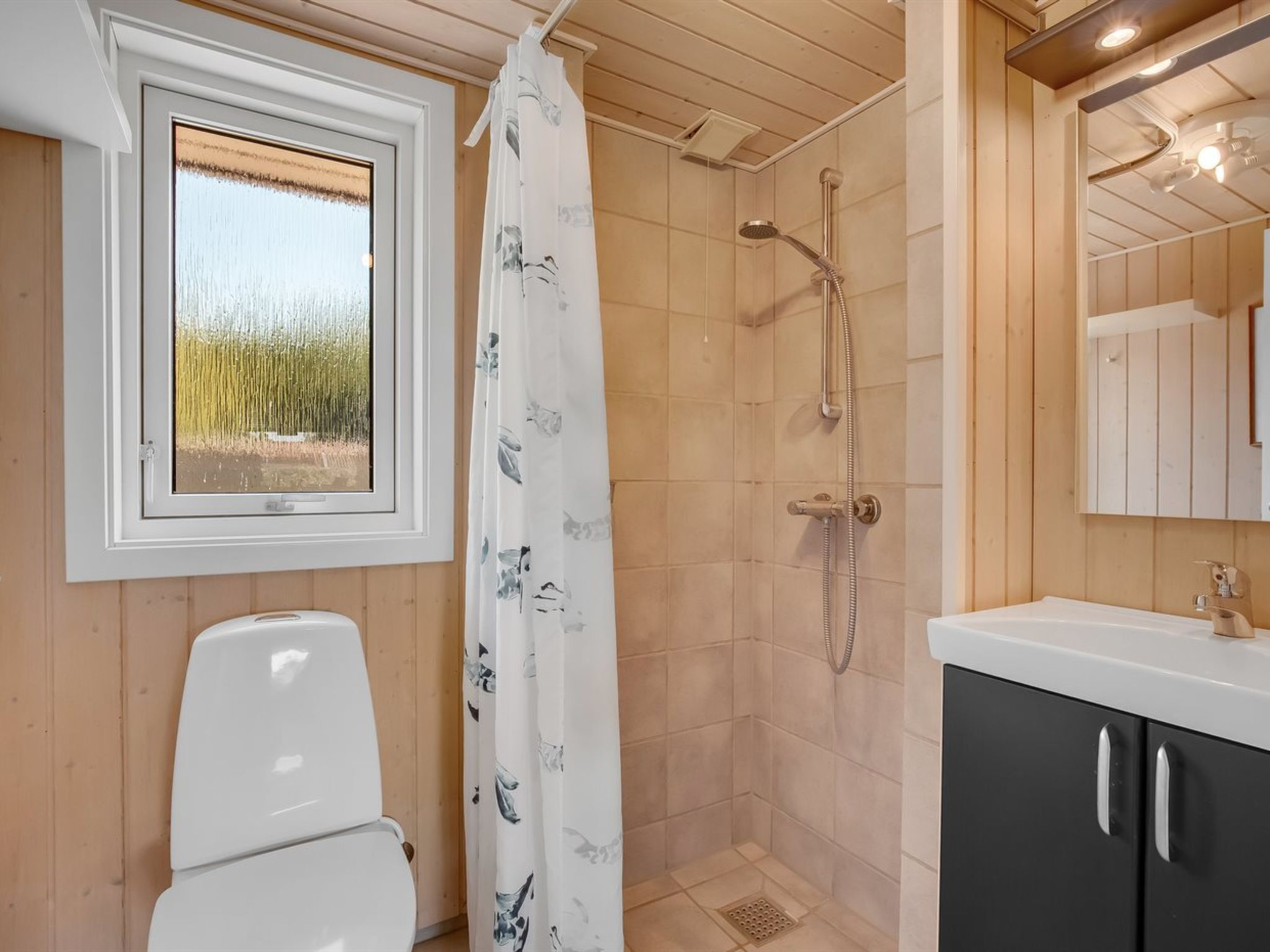 A bathroom with a shower, toilet, and sink.