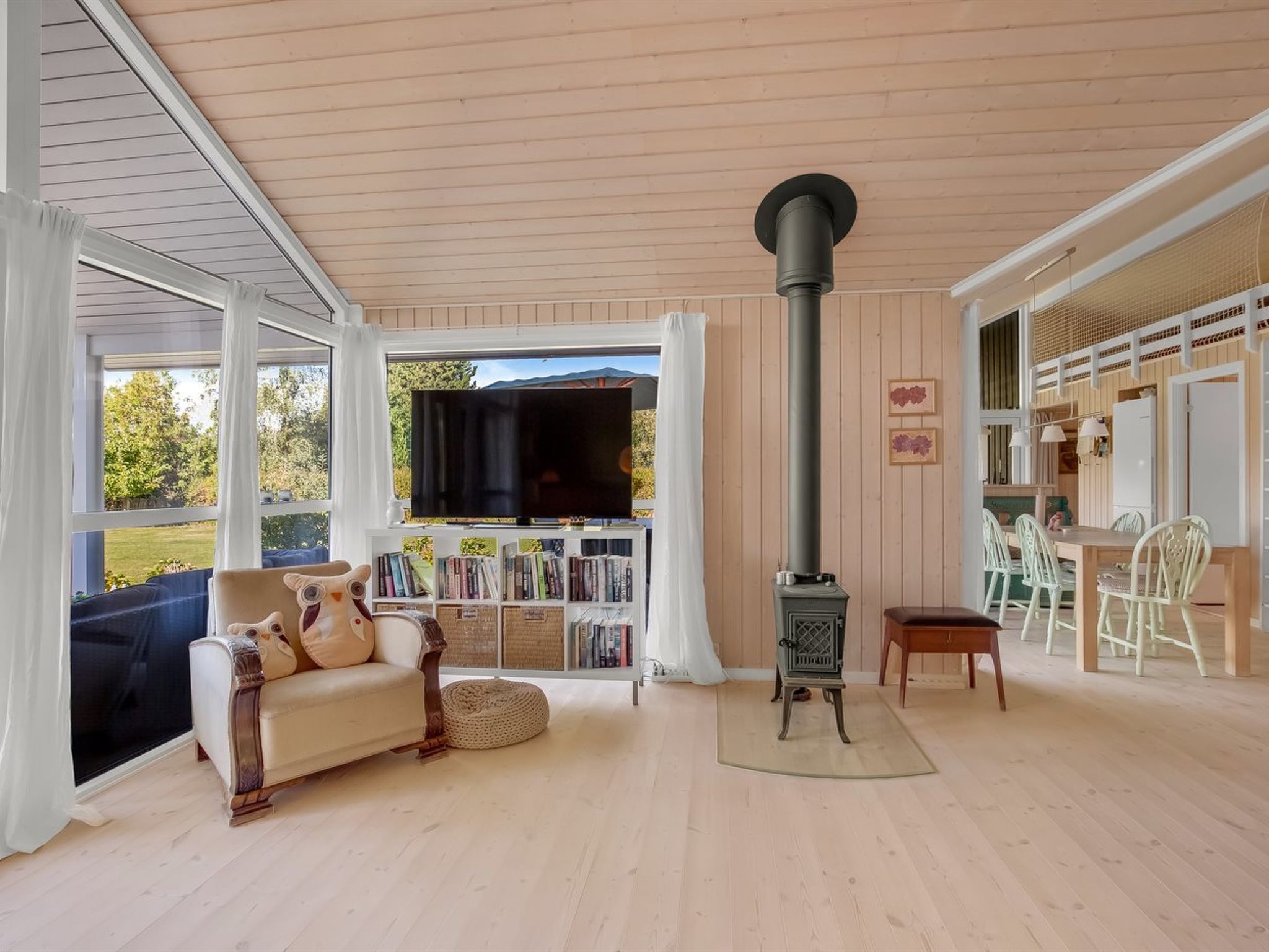 A cozy living room with a sofa, a television, a fireplace, and a dining area with chairs.