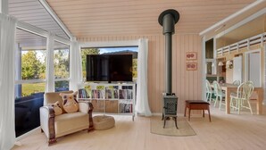 Ein gemütliches Wohnzimmer mit einer Couch, einem Fernseher, einem Kamin und einem Essbereich mit Stühlen.