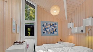Ein Schlafzimmer mit einem Bett, einem Schreibtisch, einem Fenster und einem wandmontierten Regal.