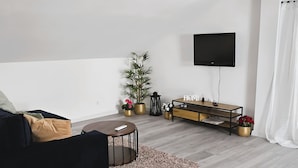 A modern living room with a sofa, a coffee table, a TV mounted on the wall, and a wooden TV stand with decorative items. - Villa Casa Mia Sabunike (Privlaka)