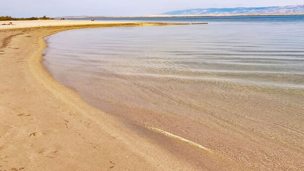 Een strand met helder water en een zandstrand.