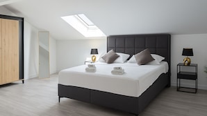 A modern bedroom with a skylight, a bed with pillows, a nightstand, and a wardrobe. - Villa Casa Mia Sabunike (Privlaka)
