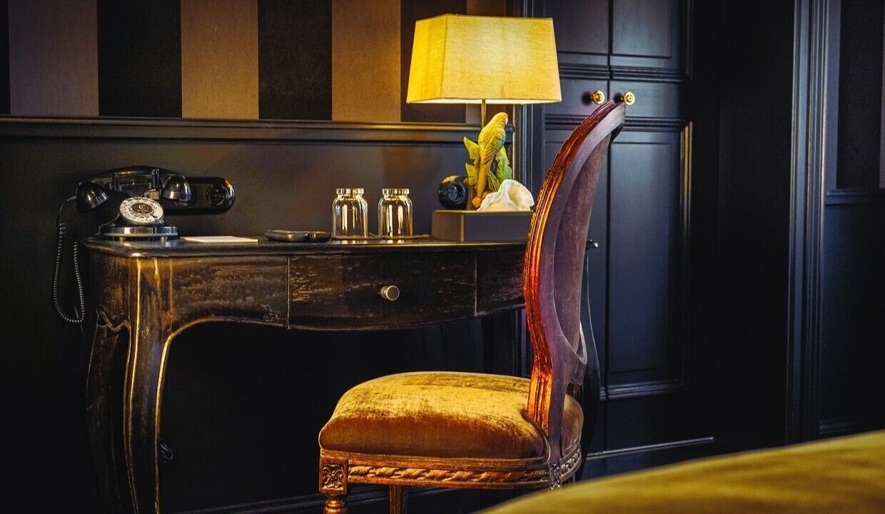 A vintage-style desk with a telephone, a lamp, and decorative items.