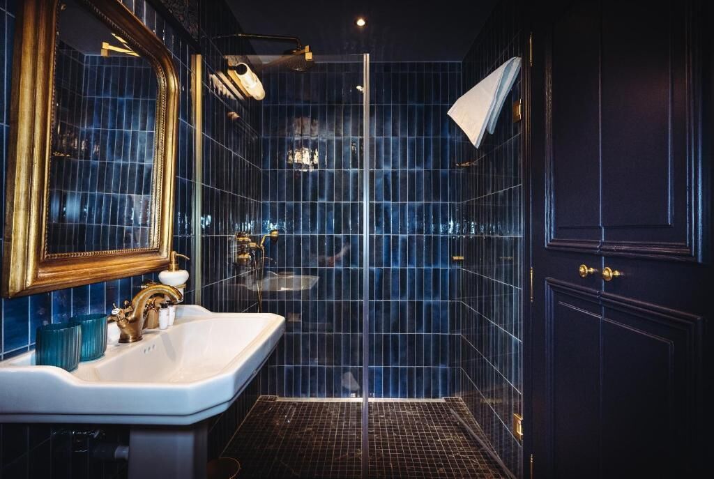 A modern bathroom with a large mirror, a white sink, and a glass shower enclosure.