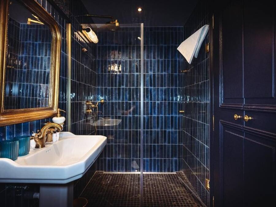 A modern bathroom with a large mirror, a white sink, and a glass shower enclosure.