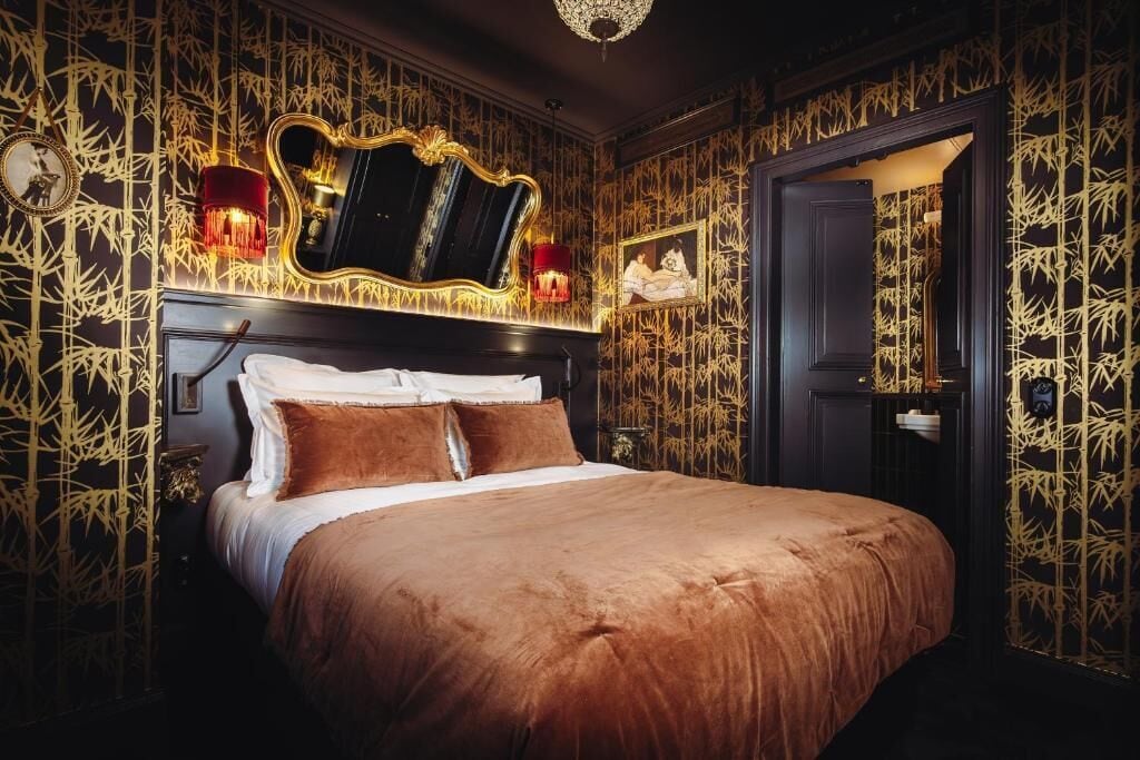 A luxurious bedroom with a large bed, a mirror, and wall-mounted sconces.