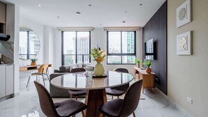 A modern dining area with a round table, dark upholstered chairs, and a vase with flowers.