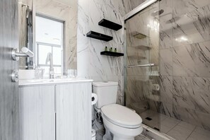 A modern bathroom with a toilet, sink, and glass-enclosed shower.