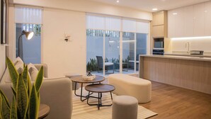 A modern kitchen with a dining area, large windows, and a view of the outdoors.