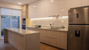 A modern kitchen with light wood cabinets, stainless steel appliances, and a granite countertop.