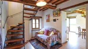 Ein gemütliches Schlafzimmer mit einer Holztreppe, einem Bett mit gemusterten Textilien, einem Fenster mit Vorhängen und einem Bild an der Wand.
