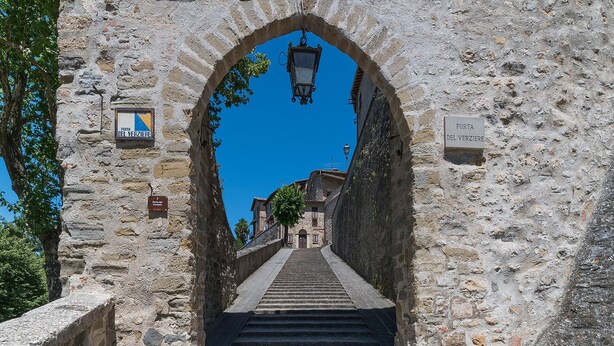 Ein steinerner Bogen, der zu einer Treppe in einer historischen Stadt führt.