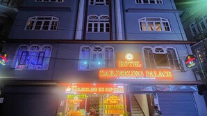 Ein Hotel namens Darjeeling Palace mit einem Schild, einem Geschäft im Erdgeschoss und einer Treppe zum Eingang.