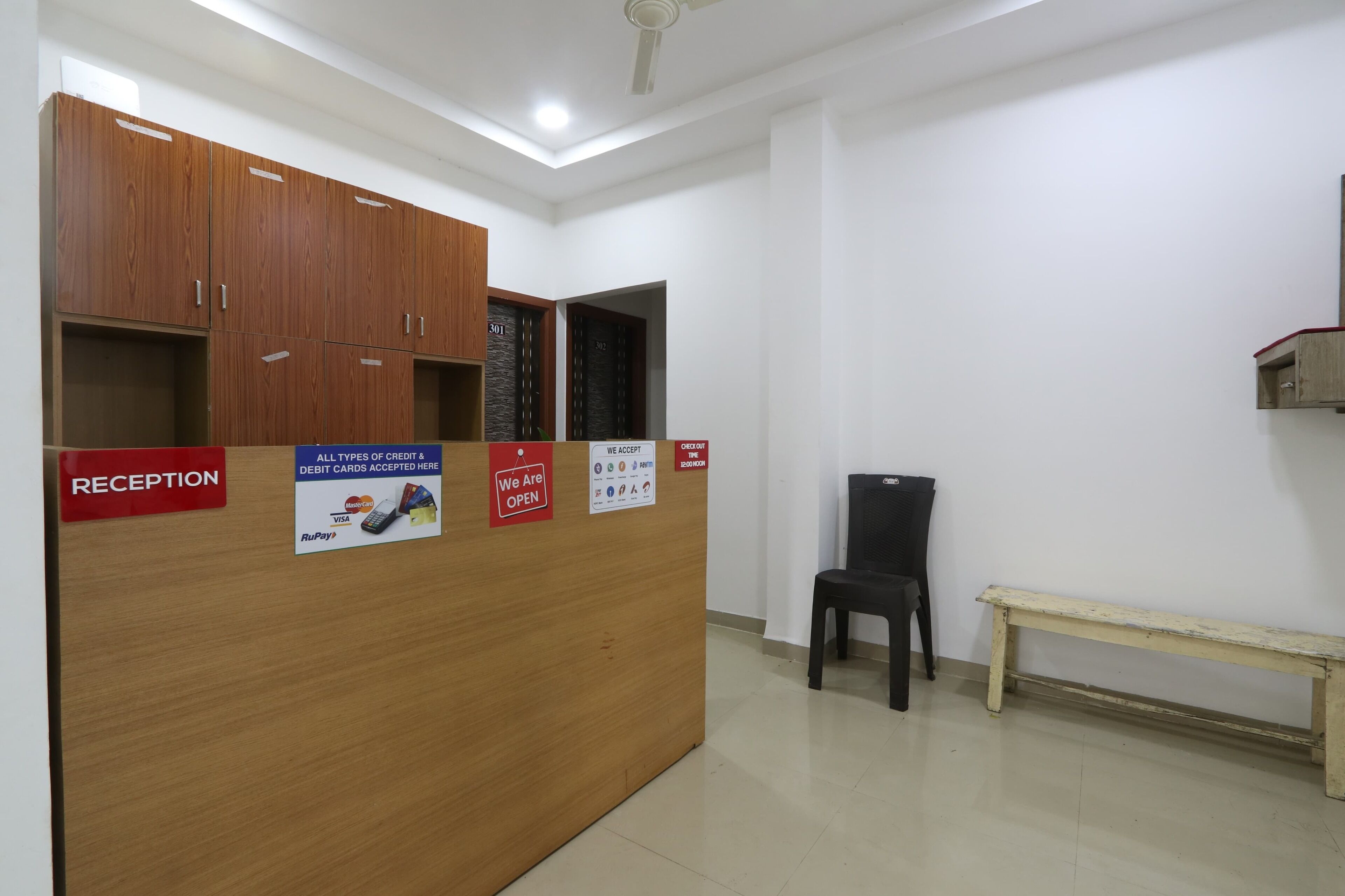 A reception desk with a wooden finish, a bench, and a wall-mounted sign indicating the reception area.