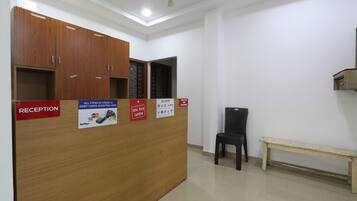 A reception desk with a wooden finish, a bench, and a wall-mounted sign indicating the reception area.