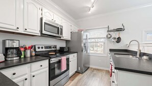 A modern kitchen with white cabinets, stainless steel appliances, a built-in oven, and a large window.