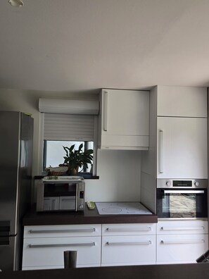 Una cocina moderna con gabinetes blancos, horno empotrado y microondas.