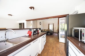 A modern kitchen with a wooden countertop, a sink, and a refrigerator.