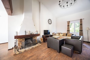 A living room with a fireplace, a sofa set, a television, and a decorative clock.