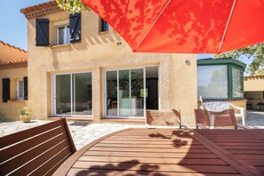 A building with a patio area, including a wooden deck and outdoor furniture.